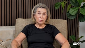 Female personal training client wearing black shirt sits in a chair to talk about her positive personal training experience as she ages.
