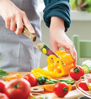 Chopping fresh vegetables for an anti-inflammatory diet to support injury recovery and physical therapy rehabilitation.