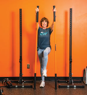 Senior client performing single-leg balance exercise with resistance band during personal training session at a physical therapy clinic.