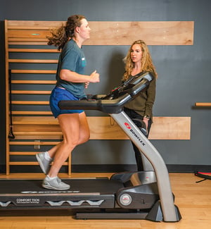 Physical therapist performing treadmill running gait analysis for injury prevention and running rehabilitation.