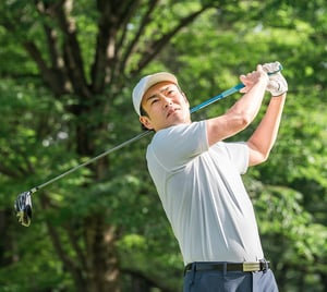 Golfer completing a swing on a course, illustrating rotational movement and mechanics addressed in sports physical therapy.