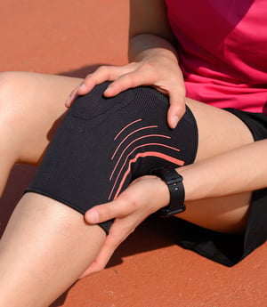 Person holding a knee with a knee brace.