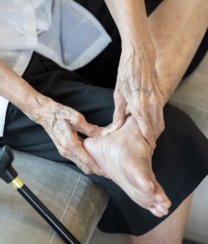 Person holding their ankle in pain.