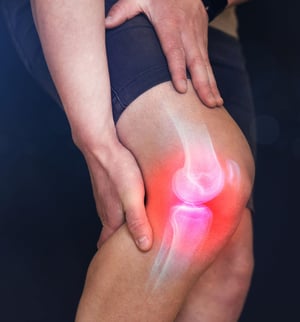 Person holding a painful knee, with highlighted knee joint.