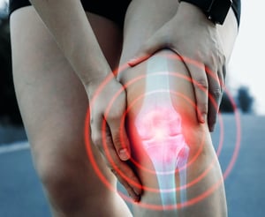 Person holding a painful knee with highlighted inflammation.
