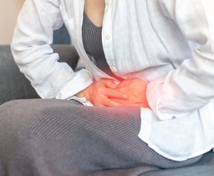 Person clutching lower abdomen, indicating pelvic pain.