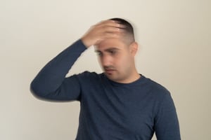 Man experiencing dizziness or head pain, holding his forehead.