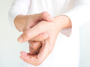 Person holding their wrist and hand, indicating wrist pain or hand joint discomfort.