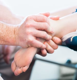 Physical therapist performing hands-on ankle mobilization during treatment.