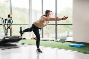 Personal trainer guiding a single-leg balance and stability exercise to improve lower body strength, coordination, and functional movement in a fitness and rehabilitation gym.