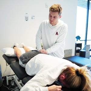 Physical therapist performing hands-on manual therapy on a patient lying on a treatment table for lower back pain relief at a physical therapy clinic.