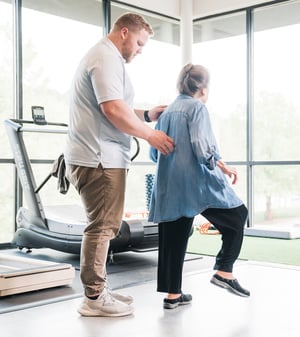 Physical therapist assisting an older adult with balance training during rehabilitation.