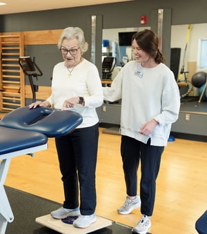 Physical therapist assisting an older adult with balance training during physical therapy.