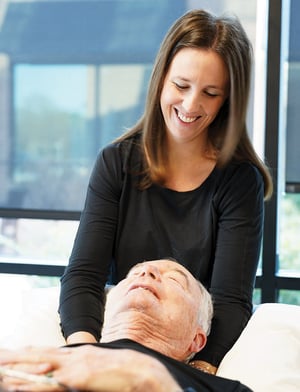 Physical therapist providing manual therapy to an older adult patient in a clinic setting.