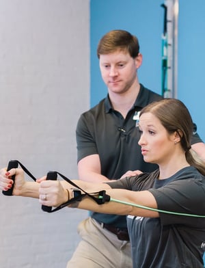 Physical therapist guiding a patient through resistance band exercise in a rehabilitation clinic.