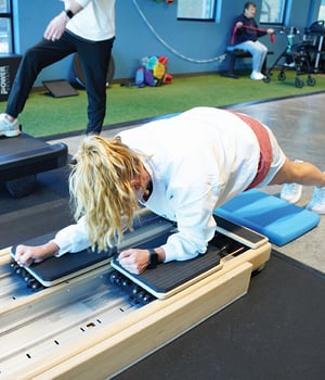 Woman performing plank exercise on gliding slide board during personal training session at EW Motion Therapy.
