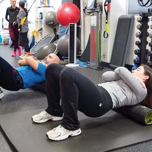Personal training clients performing core strengthening exercises during a small group training session at EW Motion Therapy.
