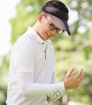Golfer experiencing wrist pain consistent with golfer’s elbow during a swing.