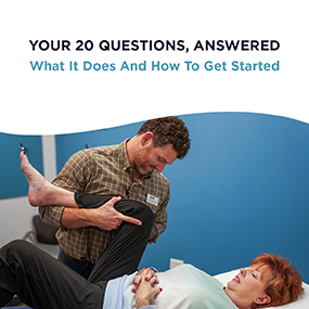 Male physical therapist stretching a female patient's leg on a treatment table in a clinical setting, representing EW Motion Therapy's free guide on what physical therapy does and how to get started