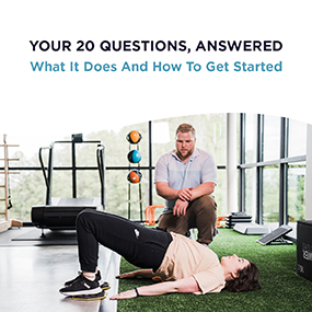 Personal trainer observing a woman performing a glute bridge on a gym floor, representing EW Motion Therapy's free guide on the benefits of personal training and how to get started
